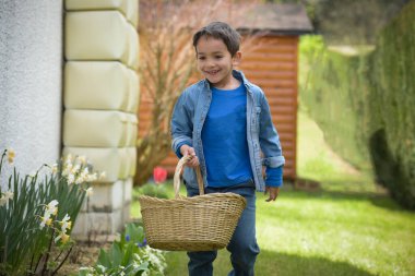Baharda bahçede paskalya yumurtası arayan bir çocuğun manzarası.