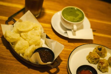 Kızarmış abur cuburlar, soslar, köpüklü buzlu içecekler ve ahşap bir masada canlı yeşil kibrit latte içeren cazip bir yemek..