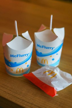 Yogyakarta, Endonezya - 16 Şubat 2024: McDonalds 'dan iki McFlurry fincanı, ahşap bir masanın üzerine gevrek bir aperatifle servis edildi. Lezzetli, kremalı bir tatlı Tazeleyici tatlı için mükemmel.