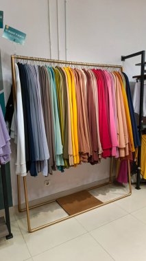 Modern moda bir butikte çeşitli renkli mütevazı elbiseler ve başörtüleri düzgün bir şekilde dizilmiş..