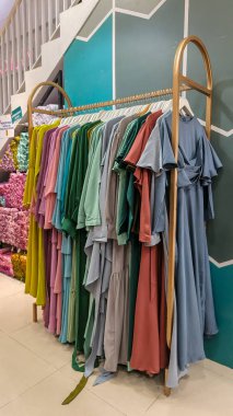 Modern moda bir butikte çeşitli renkli mütevazı elbiseler ve başörtüleri düzgün bir şekilde dizilmiş..