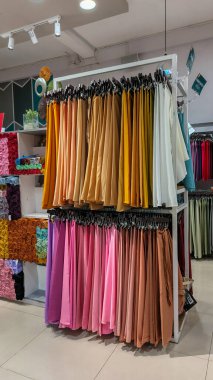 Modern moda bir butikte çeşitli renkli mütevazı elbiseler ve başörtüleri düzgün bir şekilde dizilmiş..