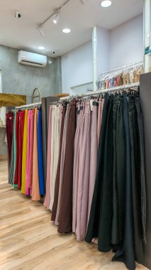 Modern moda bir butikte çeşitli renkli mütevazı elbiseler ve başörtüleri düzgün bir şekilde dizilmiş..