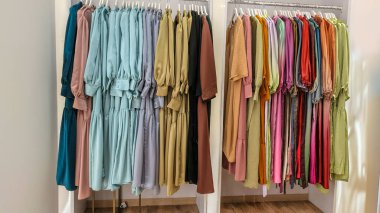 Modern moda bir butikte çeşitli renkli mütevazı elbiseler ve başörtüleri düzgün bir şekilde dizilmiş..