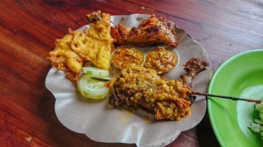 Zengin bir Endonezya usulü ızgara ördek, sambal, kızarmış tavuk, börek ve salatalık dilimleri..