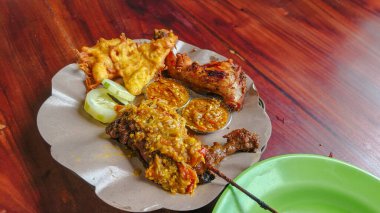 Zengin bir Endonezya usulü ızgara ördek, sambal, kızarmış tavuk, börek ve salatalık dilimleri..