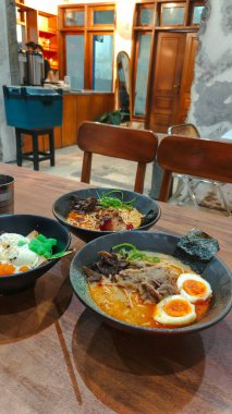 Lezzetli bir üçlü baharatlı ramen kasesi ve renkli bir tatlı. Dondurma, tost ve malzemelerle birlikte. Endüstriyel cazibesi olan, sade bir kafede servis ediliyor..