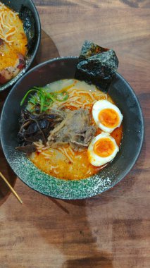 Lezzetli bir üçlü baharatlı ramen kasesi ve renkli bir tatlı. Dondurma, tost ve malzemelerle birlikte. Endüstriyel cazibesi olan, sade bir kafede servis ediliyor..