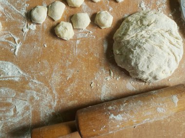 Üzerinde un, hamur ve sallanan bir sandalye serpiştirilmiş bir masa.