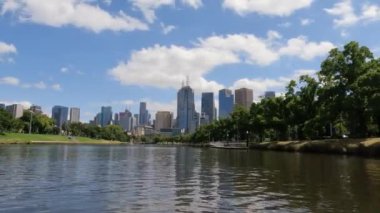 POV, Melbourne 'daki Yarra Nehri' nde güneşli bir günde gökdelenlerle birlikte süzülen bir kanonun 4K görüntüsünü taşıyor..