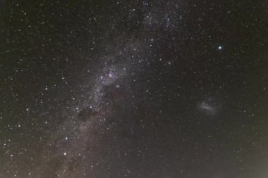Samanyolu 'nun güney yarımküre hızlandırılmış görüntüsü karanlık gece gökyüzünde dönüyor gibi görünür, Macellan, düzensiz cüce galaksiler görünür..