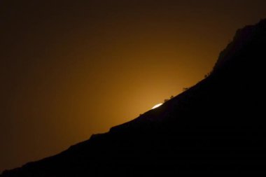 Dolunay, maden kasabası Tom Price 'ın siluetinin ardında yükseliyor. Ay 'ı göstermek için birden fazla pozlama.