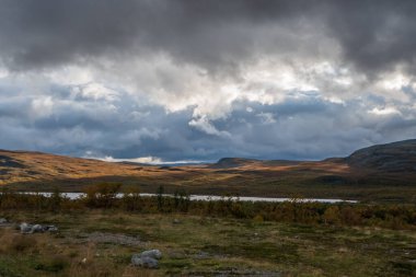 Vahşi doğada güzel bulutlu bir gün. Ortadaki küçük göl. Güneş ışığı bulutların arasından yükseliyor. Yüksek kalite fotoğraf