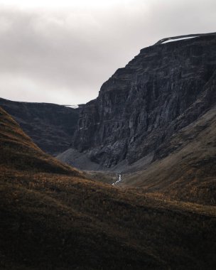 Dik uçurumu olan derin bir vadi. Vadinin dibinde bir nehir. Dikey fotoğraf.