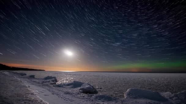 时间过去了海岸上方的星迹 月球路径和北极光 以及被冰覆盖的大海 — 图库视频影像