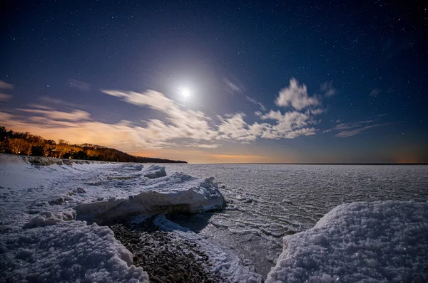 在星空和月亮的映衬下 海滨被冰覆盖 图库照片