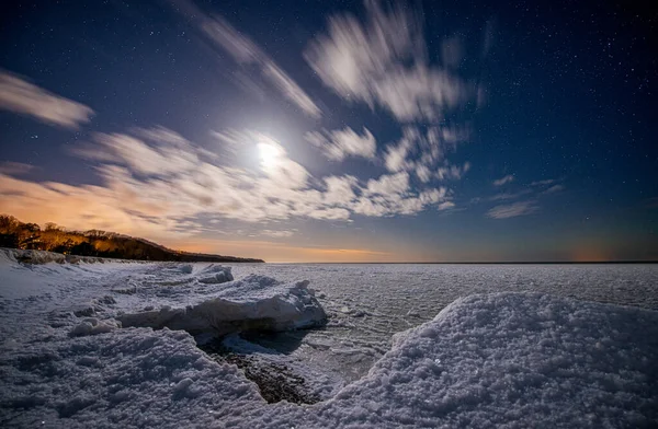 在星空和月亮的映衬下 海滨被冰覆盖 图库图片