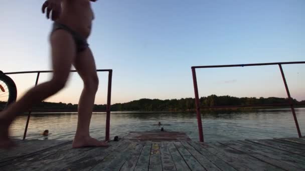 Αγόρι Πηδάει Από Μια Ξύλινη Γέφυρα Στο Ποτάμι Ένα Καλοκαιρινό — Αρχείο Βίντεο