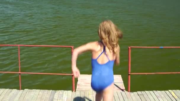 Κοριτσάκι Πηδάει Από Μια Ξύλινη Γέφυρα Στο Ποτάμι Μια Ηλιόλουστη — Αρχείο Βίντεο