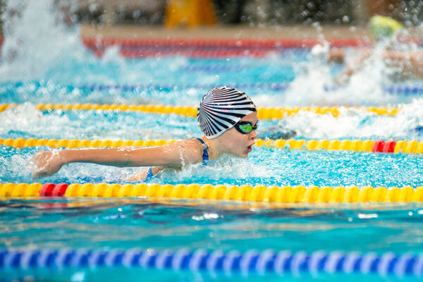Swimmer girl swims butterfly swimming style in the pool