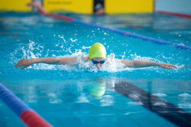 Yüzücü kız havuzda kelebek gibi yüzer.