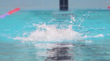 Yüzücü çocuk havuzda kelebek yüzme stili yüzer. Yavaş çekim. 