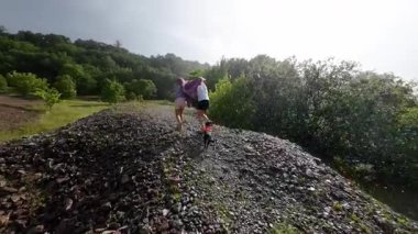 Köpekli iki küçük kız yaz yağmurunda koşuyor. Yavaş çekim.