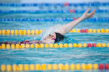 Yüzücü kız havuzda sırt üstü yüzer.