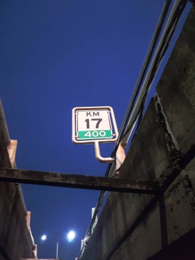 Paralı yol millajı, Endonezya otoyol tabelası akşam vakti köprünün altından çekilen koyu mavi gökyüzü. İşaretin üzerinde Kilometre 17 yazıyor. Düşük açı perspektifinden portre fotoğrafı.
