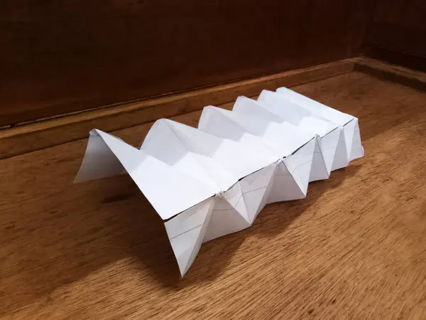 Folded paper architecture miniature model for structure study. Abstract geometric design, futuristic architectural concept.