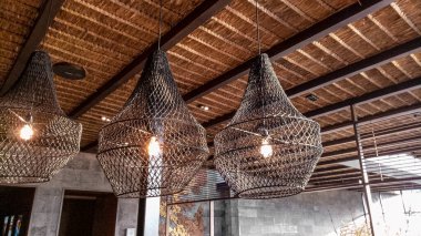 Tavana el yapımı rattan lamba asmak, tropikal titreşimler. Starbucks Reserve Dewata, Bali 'de klasik iç dekorasyon.