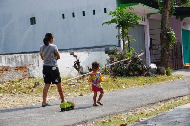 Lasem, Endonezya - 9 Ağustos 2018 Lasem caddesinde yürüyen anne ve oğul, Rembang. Yürürken oyuncak kamyon taşıyan bir çocuk. Kırsal kesimde günlük yaşam tarzı ve aktiviteler.
