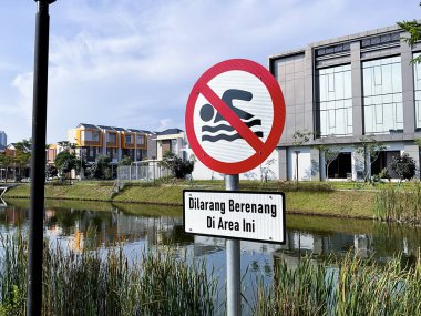Do not swim sign near a lake in Indonesian language clipart