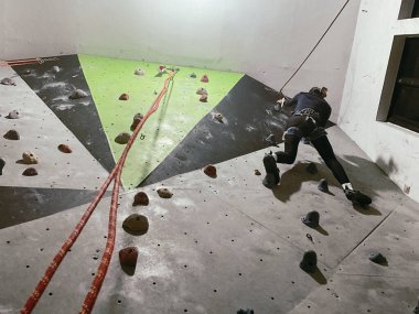 Genç kadın içeride kaya tırmanışı yapıyor, alçak açılı çekim.