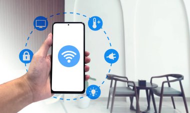Akıllı ev arayüzü kontrollü el ele tutuşan telefon, arka planda oturma odası.