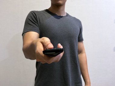 Elinde televizyon kumandası olan biri kamerayı gösterip kanalı değiştirmeye çalışıyor. Kamerada hiç yüz görünmüyor.