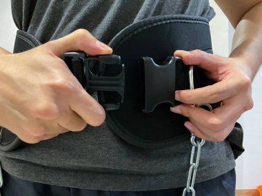 Adam halter kemerini plastik kayışla takıyor, yakın görüş. Spor salonuna hazırlanıyorum, kamerada hiç yüz görünmüyor.