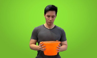 Person looking down into orange bucket, wearing dark gray t-shirt isolated on bright green screen backdrop clipart