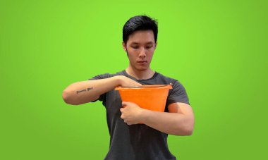 Tattooed man reaching into orange bucket looking for something. Casual wear, isolated on green screen background. clipart