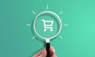 Alışveriş arabası ikonu, e-ticaret sembolü, online alışveriş ve satın alma ile el ele tutuşan büyüteç
