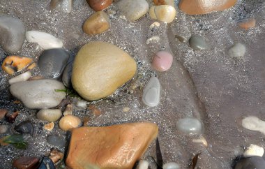 Sahilin beyaz kumsalındaki çakıl taşlarının fotoğrafı, sinematik ışıklandırmayla aydınlatılmış, inanılmaz detayları vurguluyor..