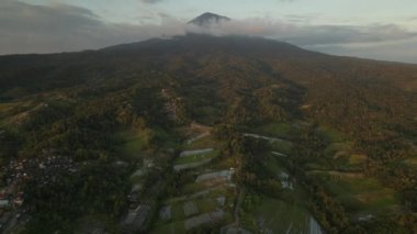 Bali 'deki Agung Dağı' nın gün batımı manzarası yeşil pirinç tarlalarıyla çevrili.