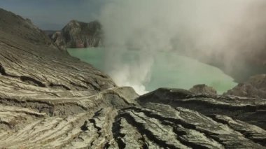Güneşli bir günde, İjen volkanı kraterindeki asit gölü üzerinde İHA uçuşu.