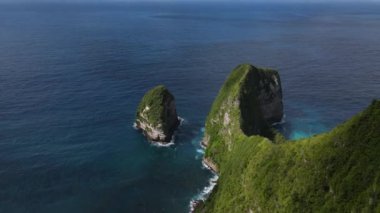 İkonik Kelingking sahilinin insansız hava aracı görüntüsü. En sonunda kamera eğimli bir masa üstü görünümü. Güneşli bir gün, dalgalar, uçurumlar, okyanuslar.
