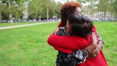 İki bayan arkadaş parkta birbirlerine sarılırlar ve mutludurlar. Çeşitlilik ve birliktelik kavramı.