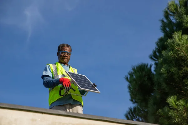 A worker installs a solar panel on a roof, renewable energy and energy crisis