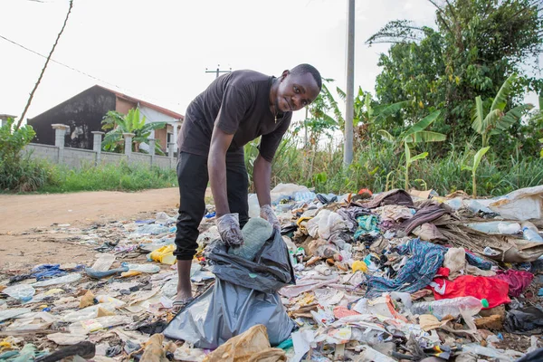 Jovem Homem Africano Olha Para Câmera Enquanto Coleta Resíduos Chão — Fotografia de Stock