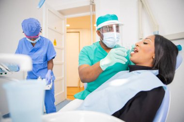 Afrika 'daki bir kliniğe dişçi muayenesi. Doktor diş aletlerini kullanırken hasta ağzını açıyor.