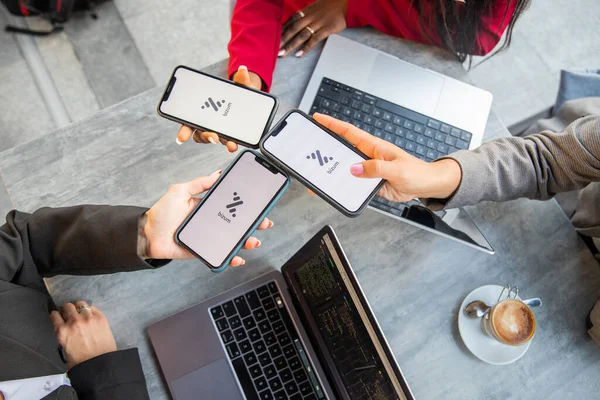 Three businesswomen during a meeting pay the bill with Bizum, a fast money exchange system