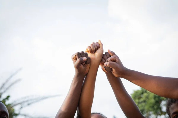 Four fists of African people united in sky, photo with copy space above